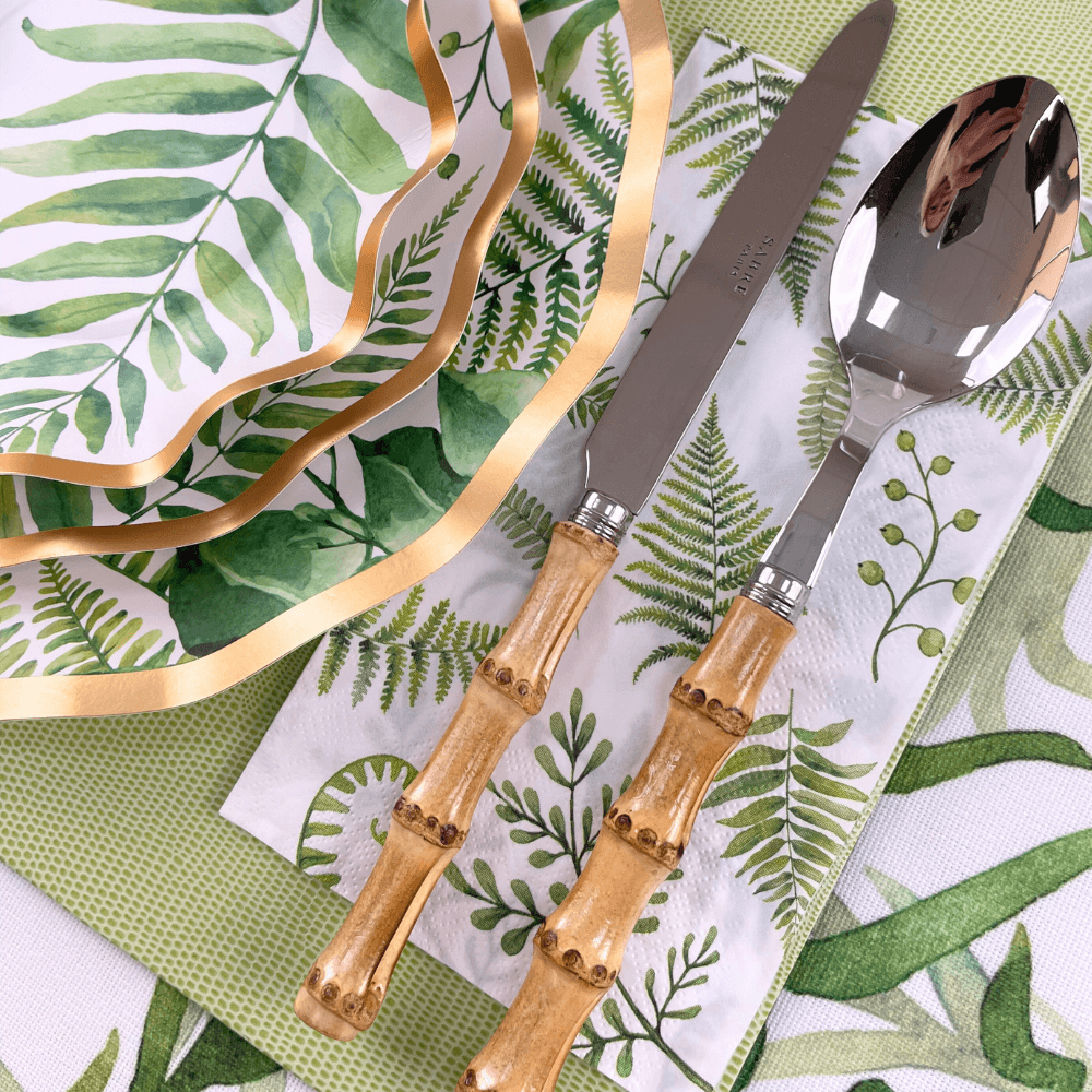 Fern &amp; Foliage Paper Guest Towel Napkins on a napkin with a spoon and knife. Elevate your party with elegance. Perfect for any event. From Party Social, your go-to for party essentials.