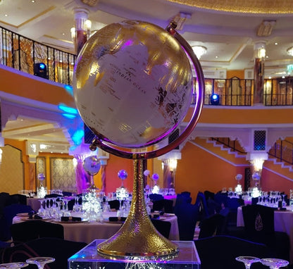 GLOBE CENTERPIECE on a stand, shown in an indoor setting with tables and chairs, ideal for adding elegance to corporate event decorations.