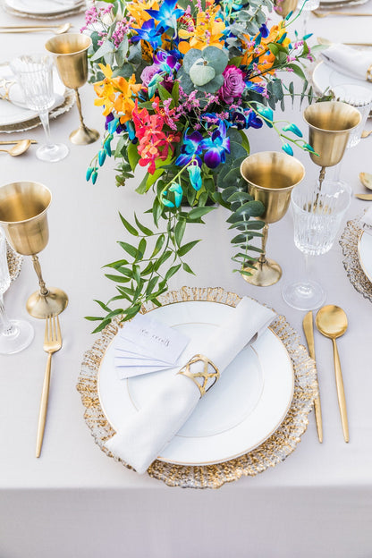 CHARGER PLATE - GOLD LEAF on a table setting with gold and white plates, floral centerpiece, enhancing an elegant event atmosphere.