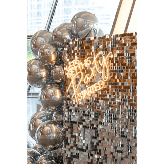 Let's Get This Party Started- LED Neon Sign amidst silver balloons, ideal for creating a lively backdrop or photo wall at events.