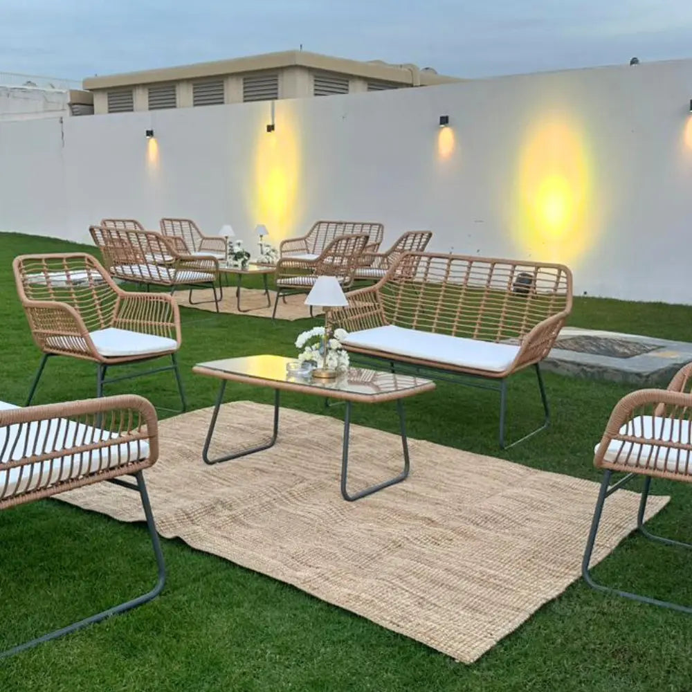 Outdoor patio set with wicker furniture on a grassy area.