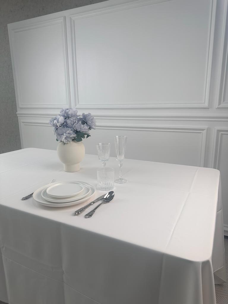 A table set with plates, silverware, and a vase of flowers.