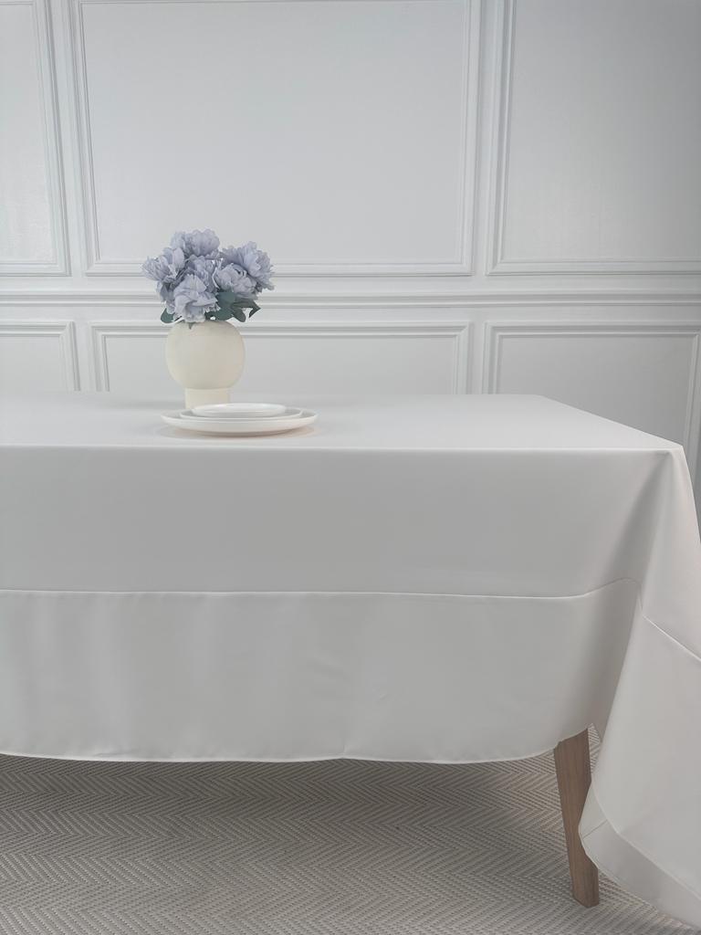 A Polycotton Tablecloth with a vase of flowers on a white table.