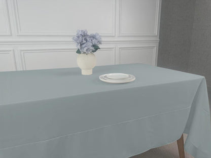 A Polycotton Tablecloth with a vase of flowers and white plates on a table.