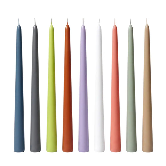 Nine taper candles in assorted colors, including blue, gray, lime green, rust orange, lavender, white, coral pink, sage green, and beige, arranged upright in a row against a plain white background.
