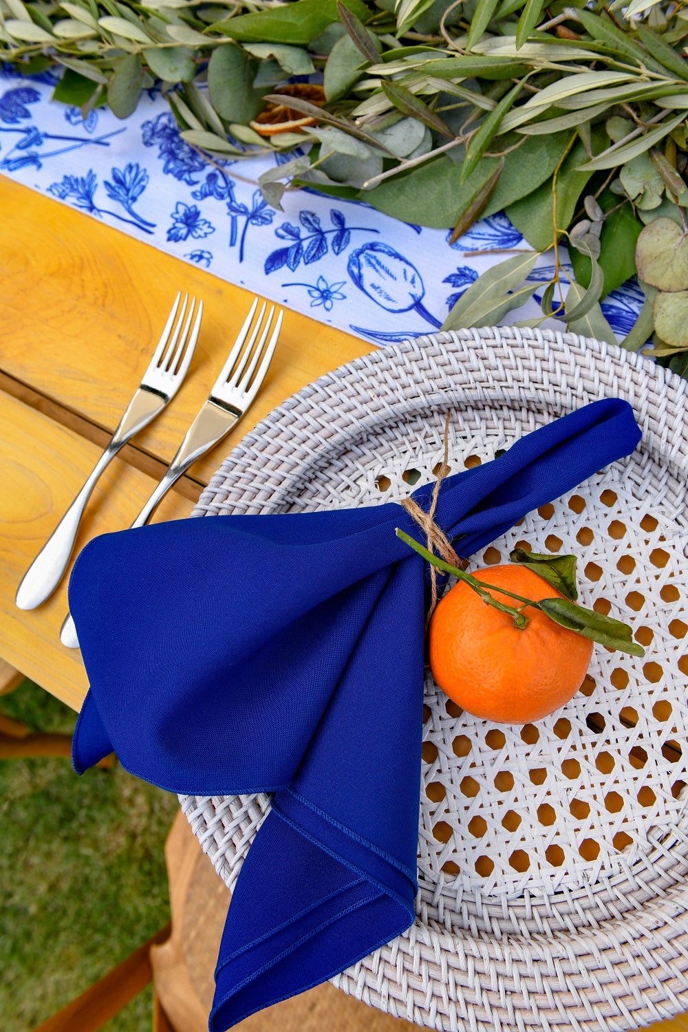 Rattan charger plate on a table setting with an orange and silverware, ideal for rustic or boho-themed events.