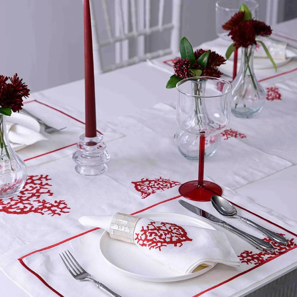 Red Coral Pure Linen Dinner Napkin set on a white tablecloth with red coral embroidery, complemented by red-stemmed glasses, stainless cutlery, and red taper candles.