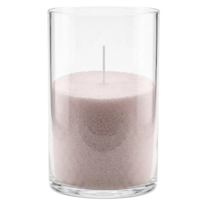 A pink wax candle in a tall, clear glass cylinder container with a single white wick, shown against a plain white background.
