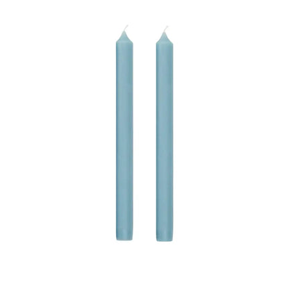 Two tall, slender light blue taper candles standing upright side by side on a plain white background.