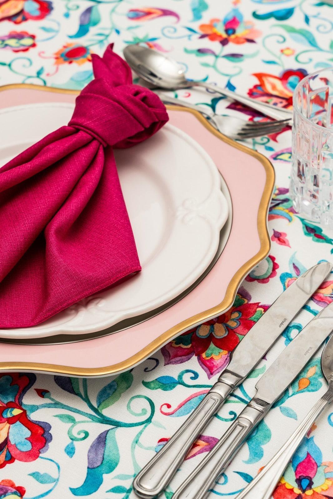 A folded napkin on a plate, accompanied by silverware on a table.