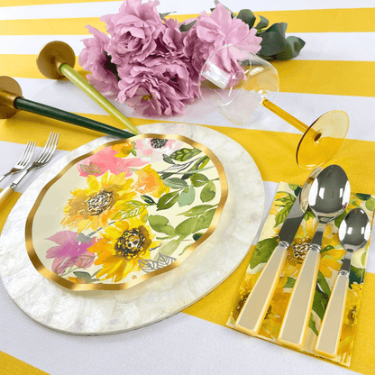 Yellow Stripe Linen Tablecloth on a table set with a floral plate, silverware, and pink flowers, enhancing a dining setup.