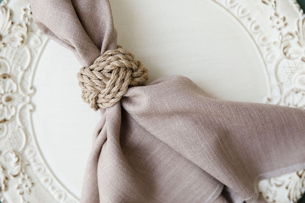 A linen blend napkin with an elegant knot detail, perfect for adding a touch of sophistication to any event. Available in various colors. Dimensions: Cocktail Napkin (25cm L x 25cm W), Dinner Napkin (50cm L x 50cm W). From Party Social.